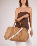 Woman holding a tan duffel bag with a white background
