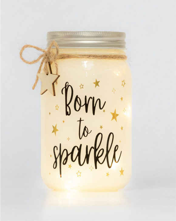 Candle in a jar with 'Born to Sparkle' text and star decorations on a light background