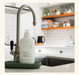 White bottle with 'Eldre & Lu' branding on a kitchen counter next to a faucet.