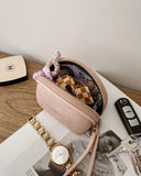 Pink Faux leather pouch with items on a magazine, next to a watch and keys.