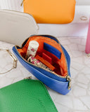 Colorful faux leather pouches with a Gucci lip balm on a textured surface
