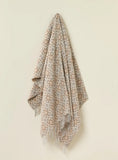 Patterned throw blanket draped over a chair on a beige background