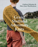 Book cover of 'Grand Shetland Adventure Knits' with a person wearing a knitted yellow shawl in a natural setting.