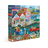 Jigsaw puzzle box with a colorful illustration of a coastal scene featuring a general store, boats, and people.